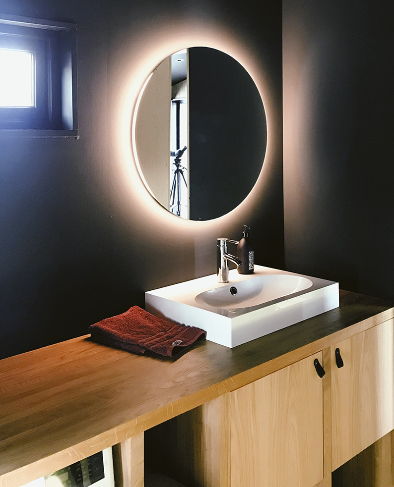 Bagno con mobile in legno e specchio rotondo illuminato dalla strip LED flessibile LINDT.