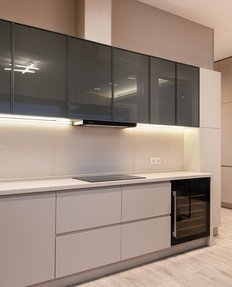Cucina moderna lineare con basi bianche opache, pensili in vetro fumé lucido e top bianco. Illuminazione a LED sotto i pensili.