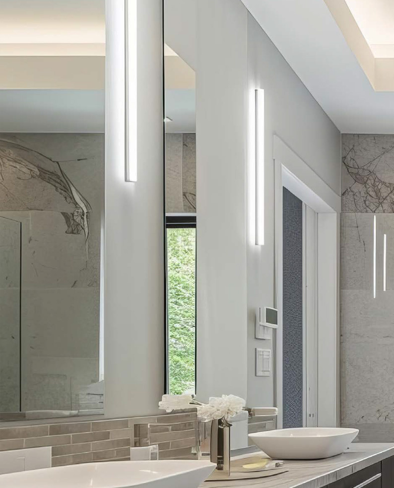 Due specchi divisi dalle lampade MASCARE posizionate verticalmente sul muro di un ambiente bagno.
